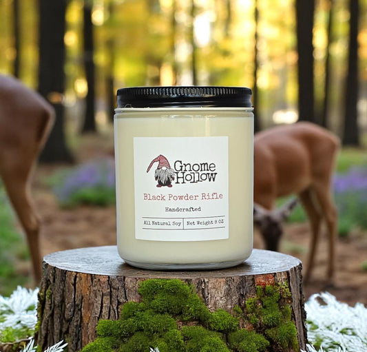 Black Powder Rifle candle sitting on a log with deer in the background
