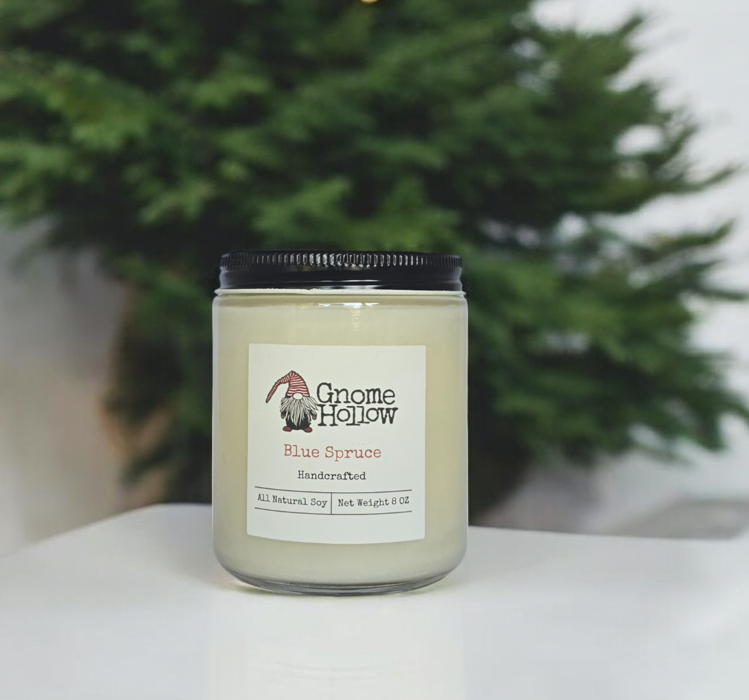 Blue Spruce candle on a white counter with a spruce tree in the background
