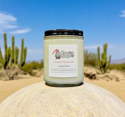 Cactus Blossom candle placed on a rock in a desert setting with cacti in the background.
