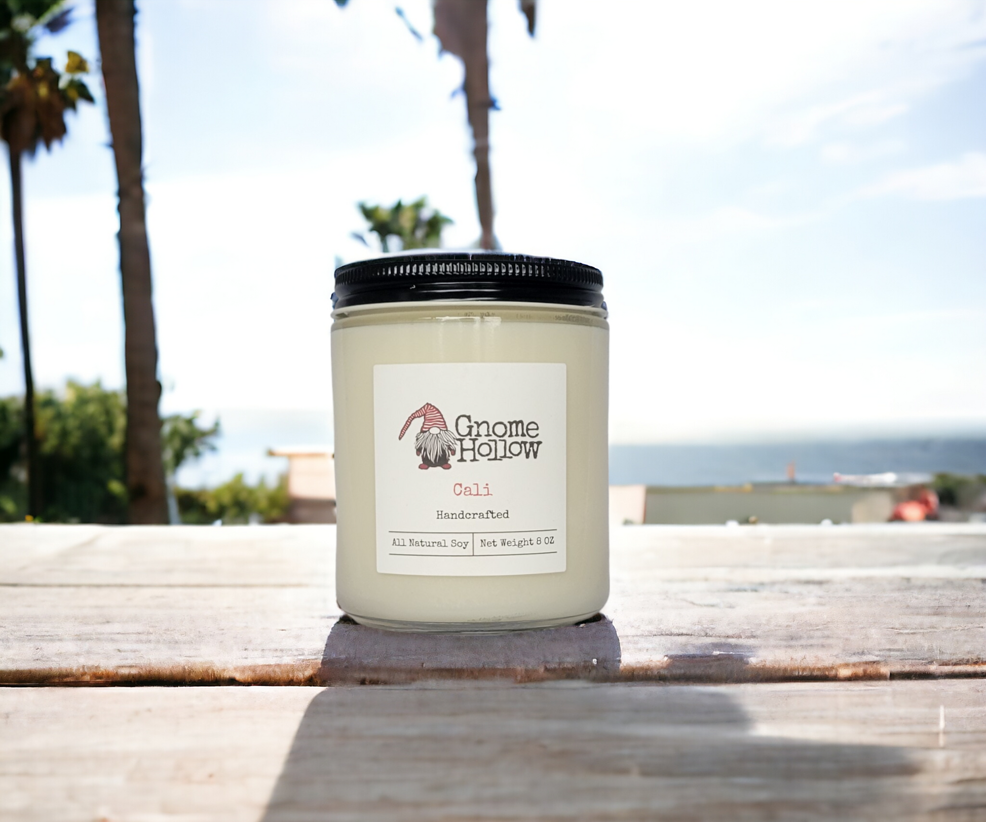 Cali candle sitting on a picnic table with the beach and ocean in the background