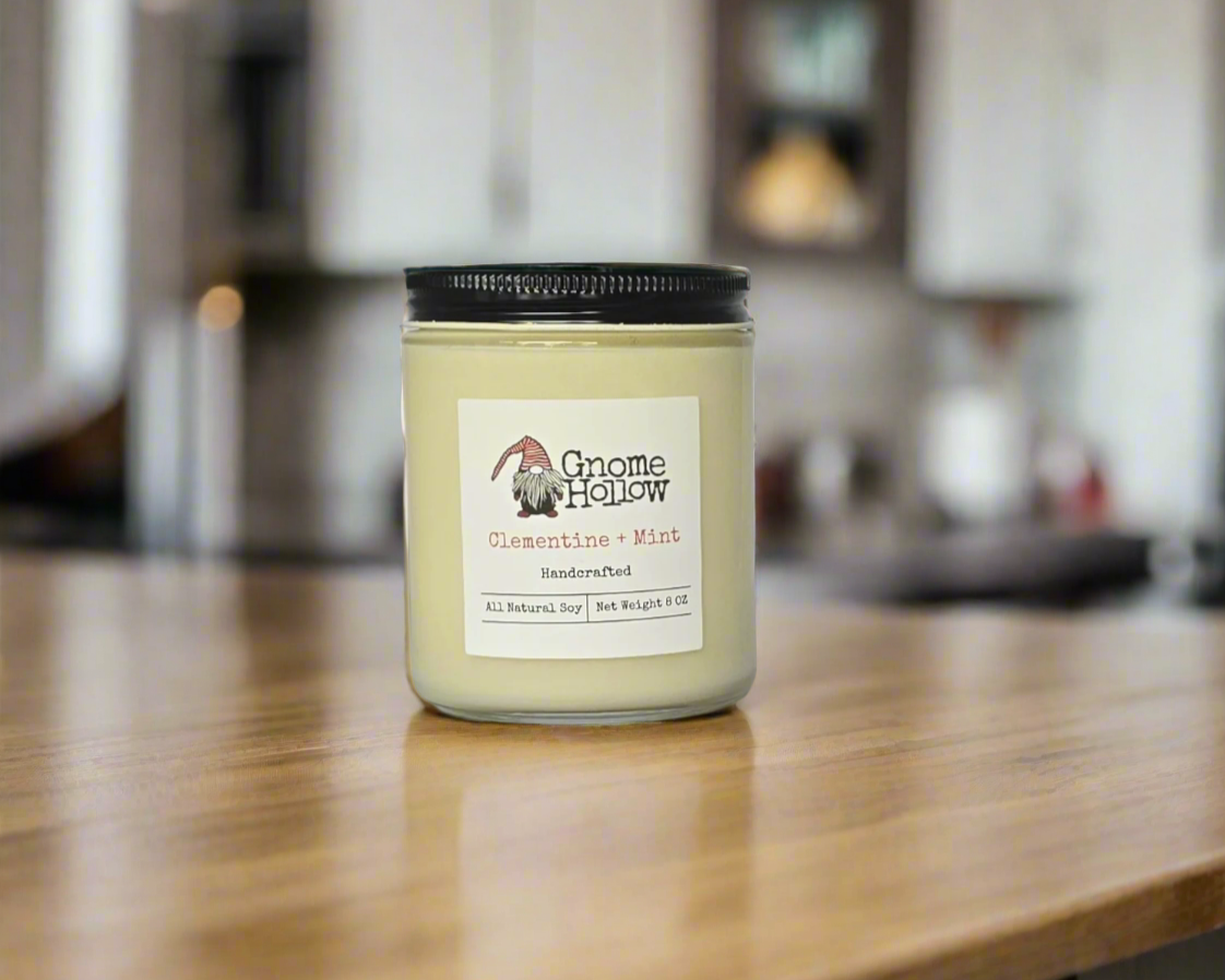 Clementine + Mint candle sitting on a wood kitchen counter with the kitchen blurred in the background
