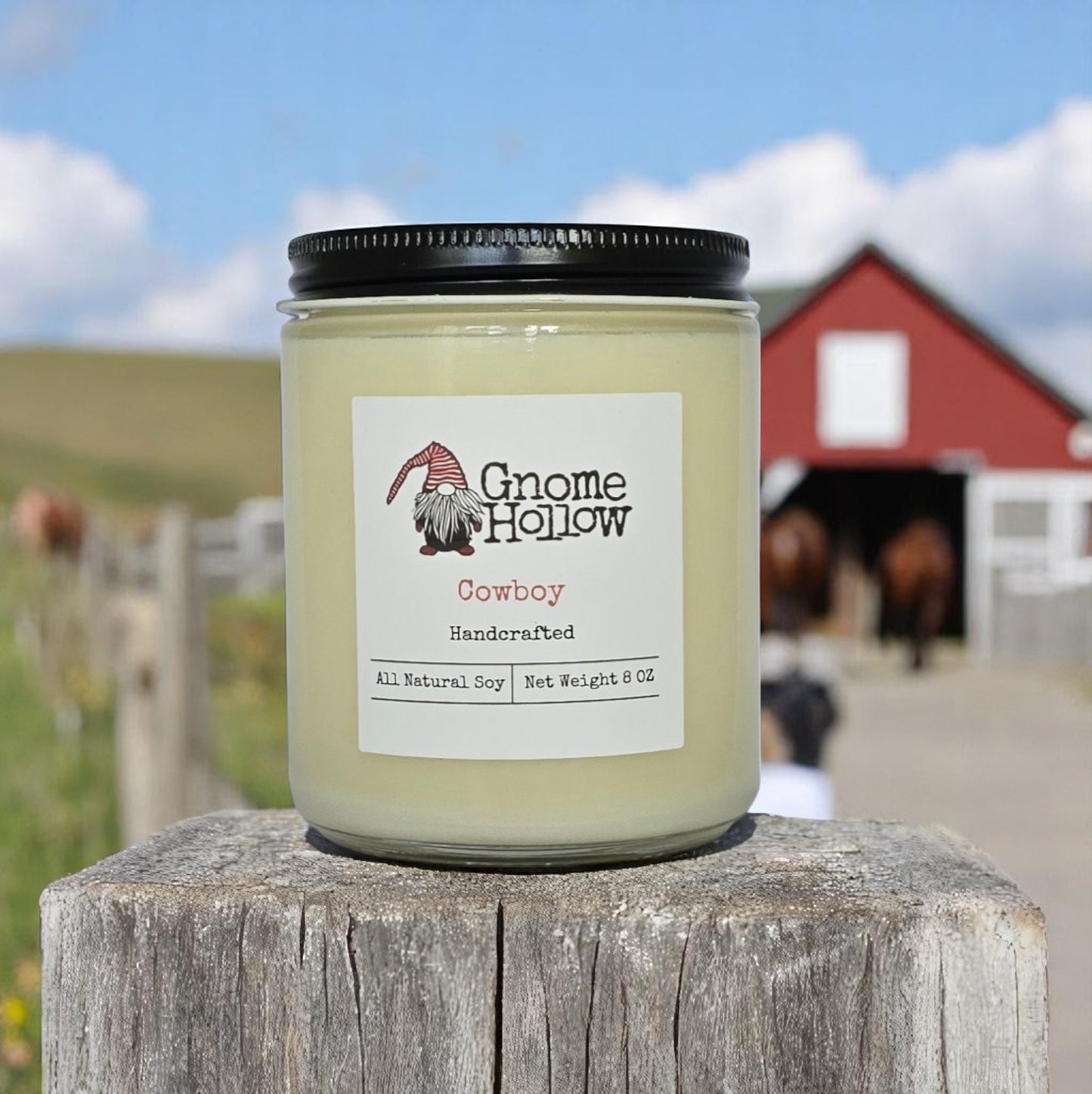 Cowboy candle placed on a wooden post with a red barn and horses in the background