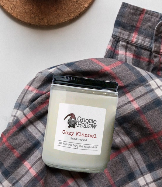 Cozy Flannel candle on a plaid fabric with a cup of coffee and a coaster.