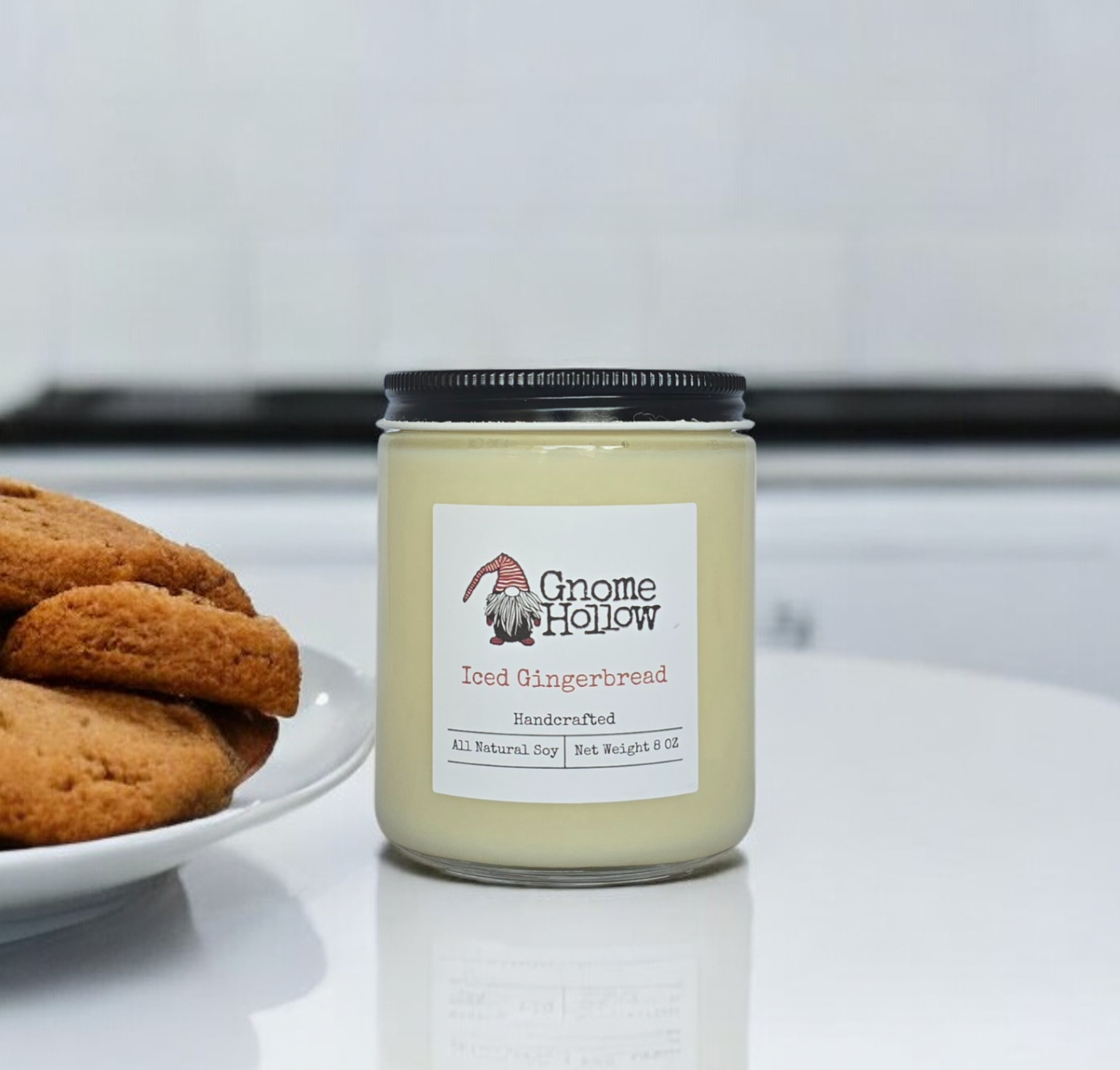 Iced Gingerbread candle placed on a kitchen countertop with a plate of gingerbread cookies in the background.