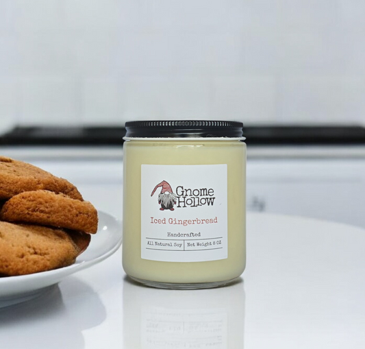 Iced Gingerbread candle placed on a kitchen countertop with a plate of gingerbread cookies in the background.