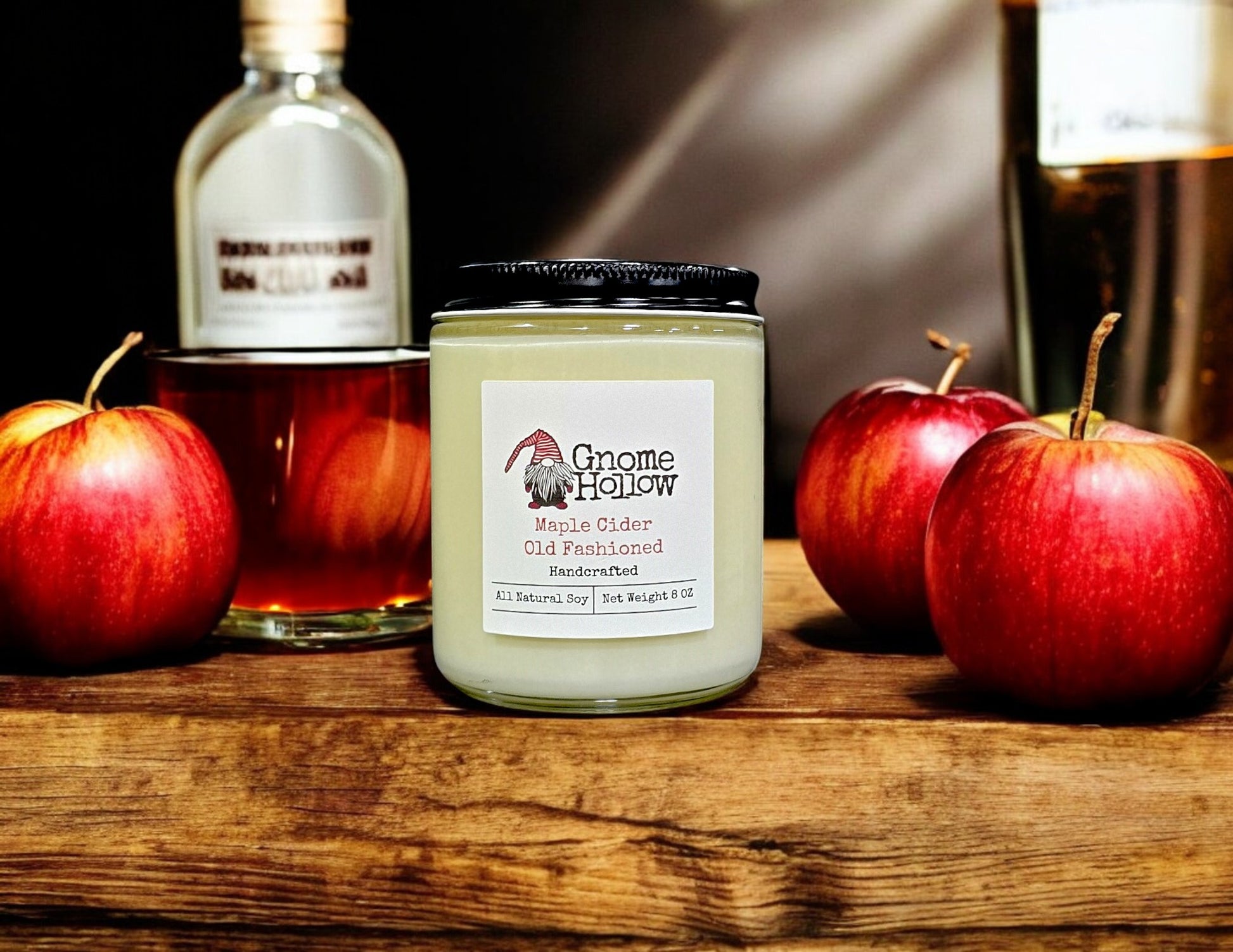Maple Cider Old Fashioned candle sitting on a wood bar with apples and a glass of bourbon