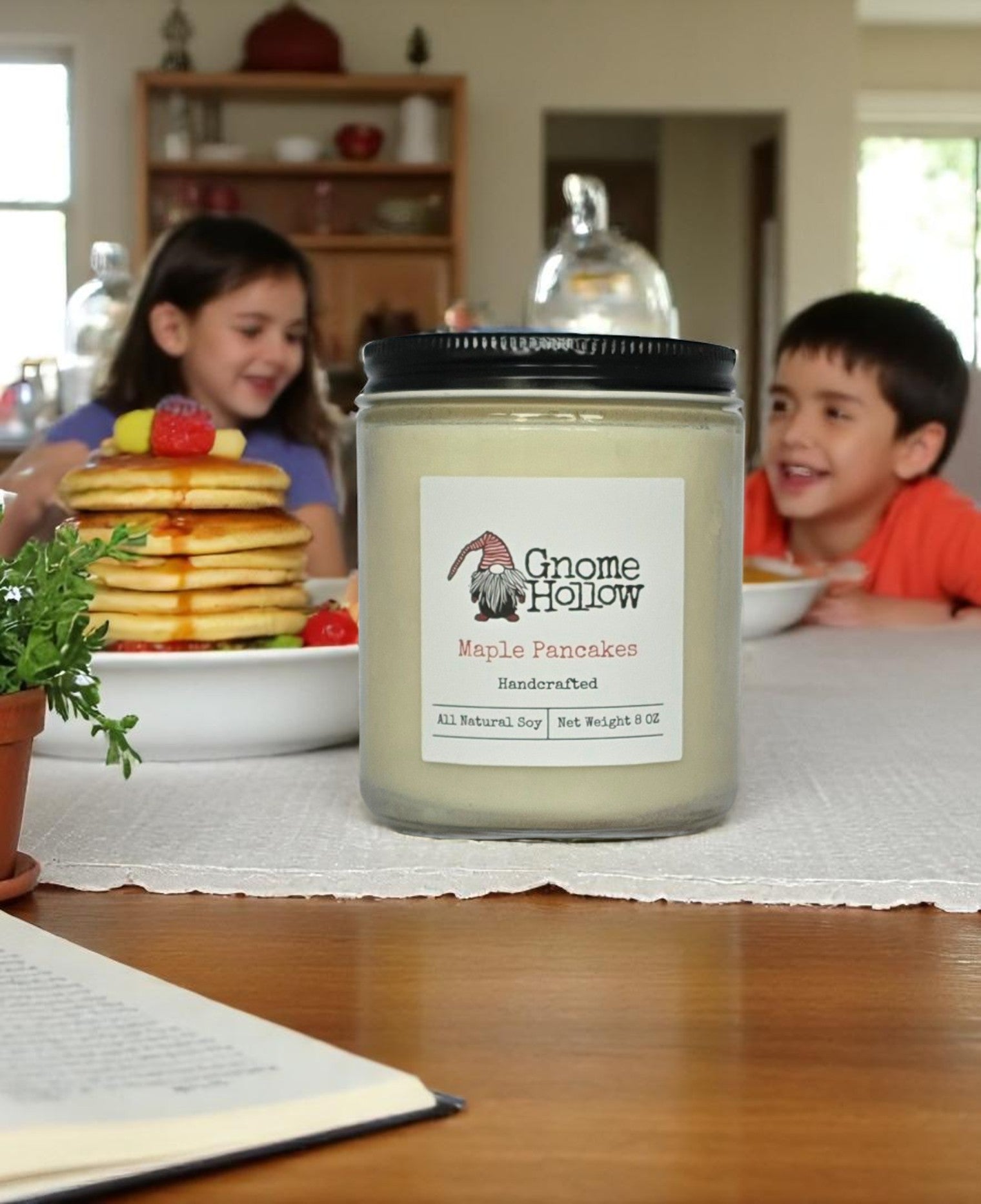Gnome Hollow candle labeled 'Maple Pancakes' on a table with children and pancakes in the background