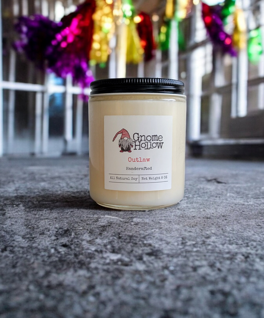 Outlaw candle on a textured surface with colorful lights in the background