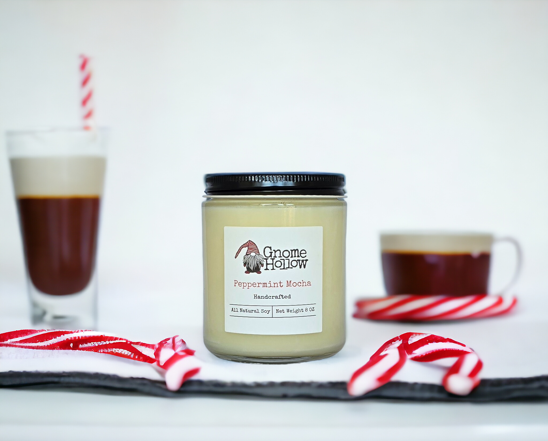 Peppermint + Mocha candle sitting on a white counter surrounded by candy canes and mocha cups