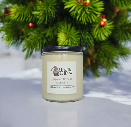 Sugar Spruce candle sitting on a white counter with evergreen and berries in the background