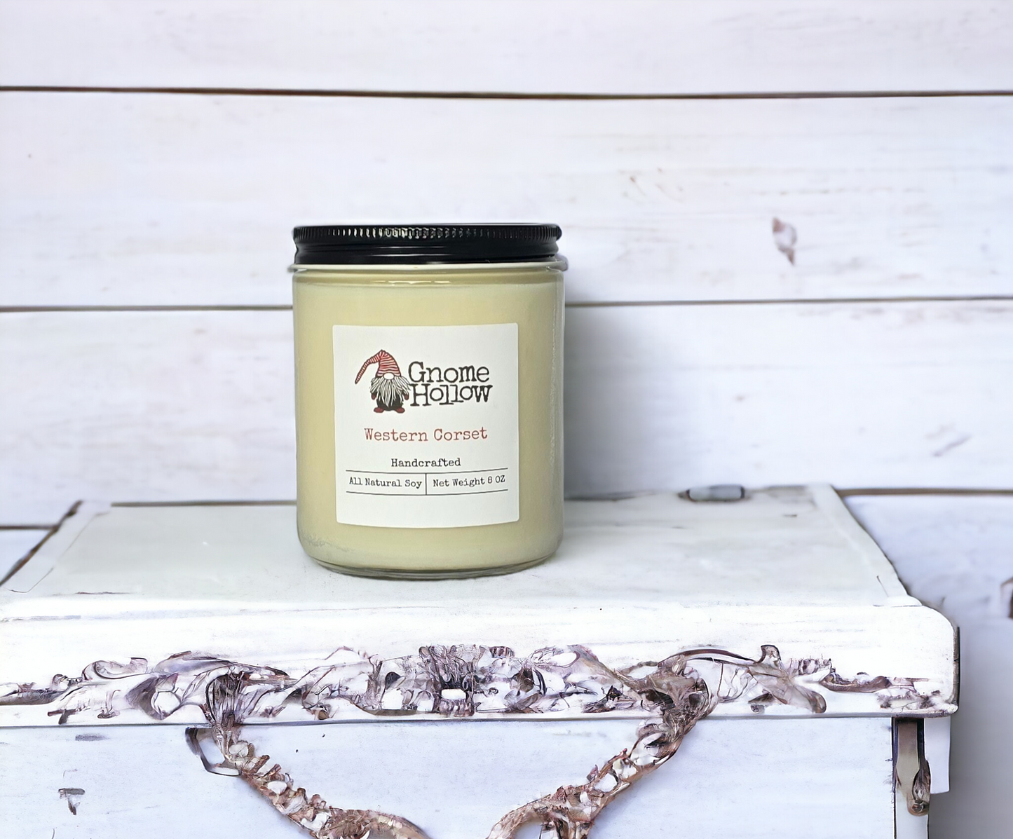 Western Corset candle placed on a white surface with a wooden background.