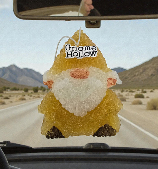 Gnome-shaped air freshener with 'Gnome Hollow' text hanging from a car's rearview mirror.