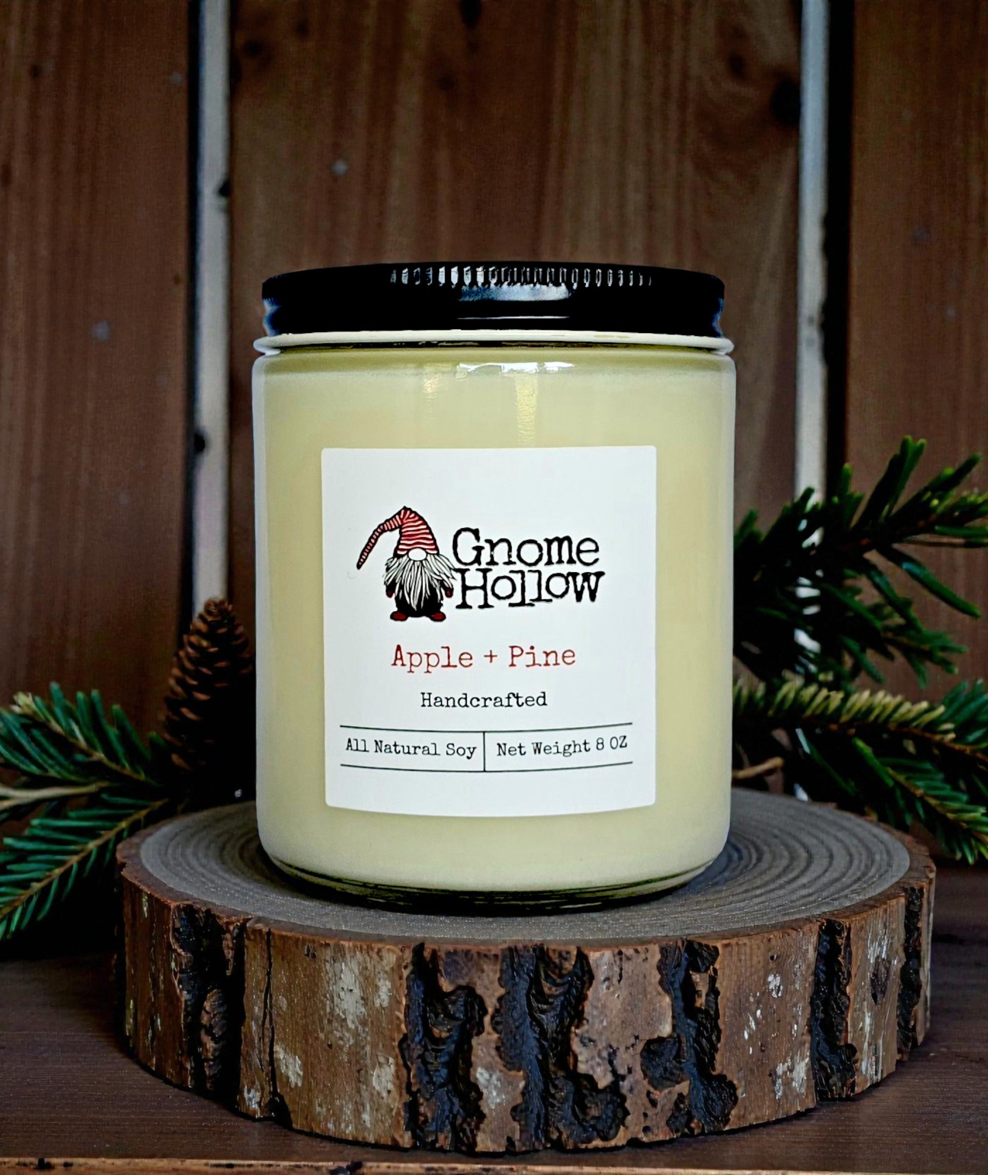 Candle on a round wood piece with pine limbs in background