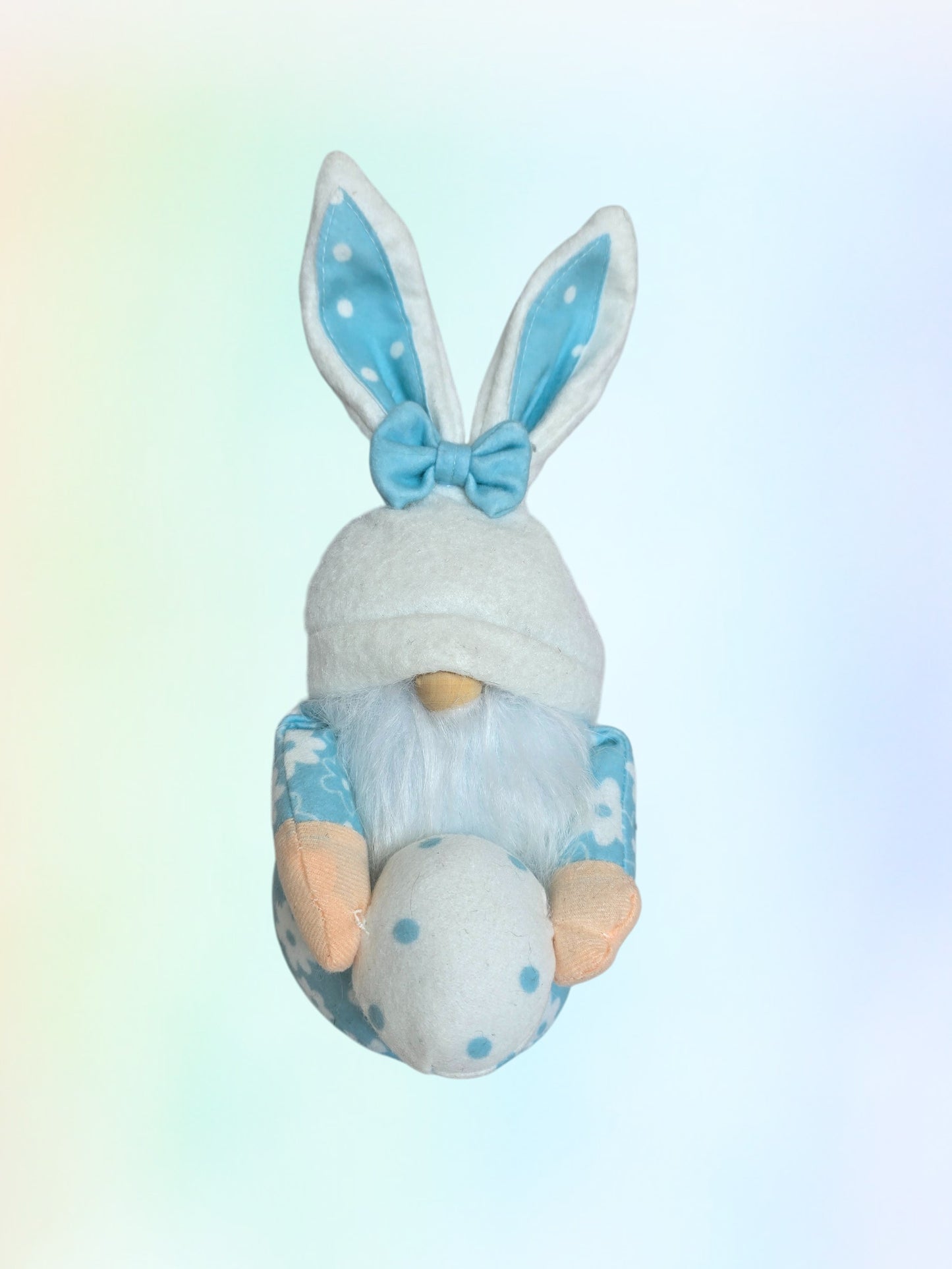 Gnome with bunny ears and a bow tie holding an egg on a gradient background
