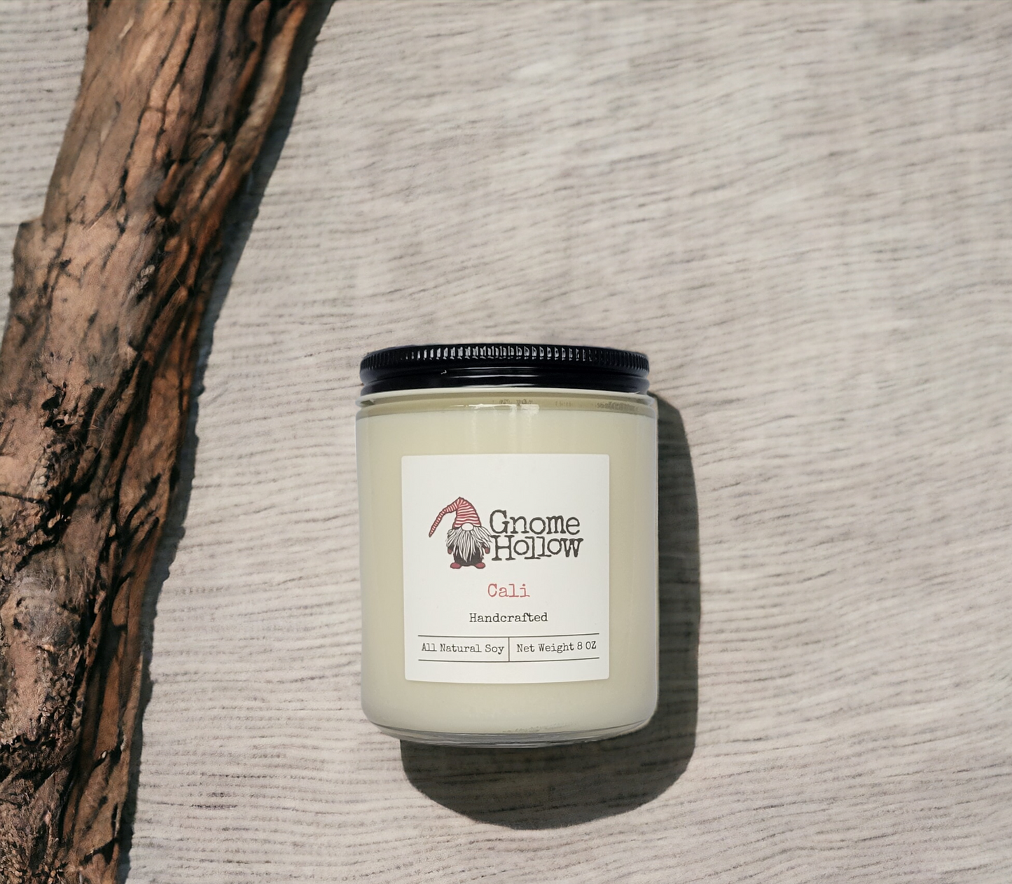 Cali candle laying next to a piece of wood