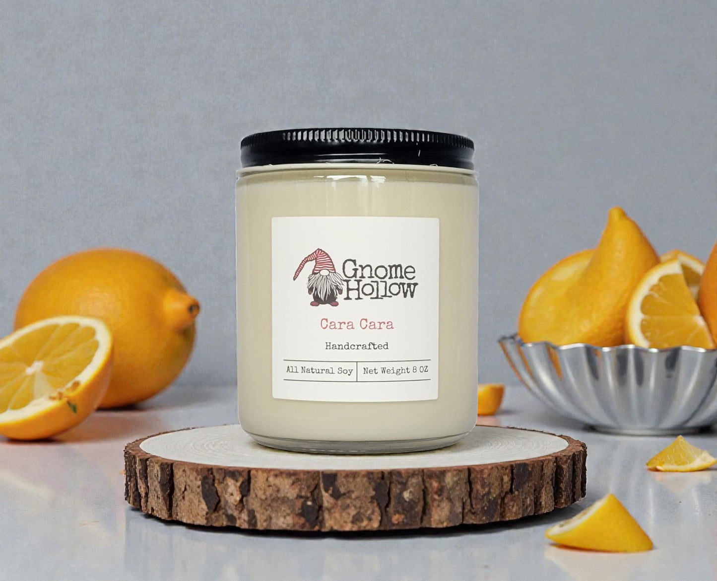 Candle on a wood circle with oranges in the background