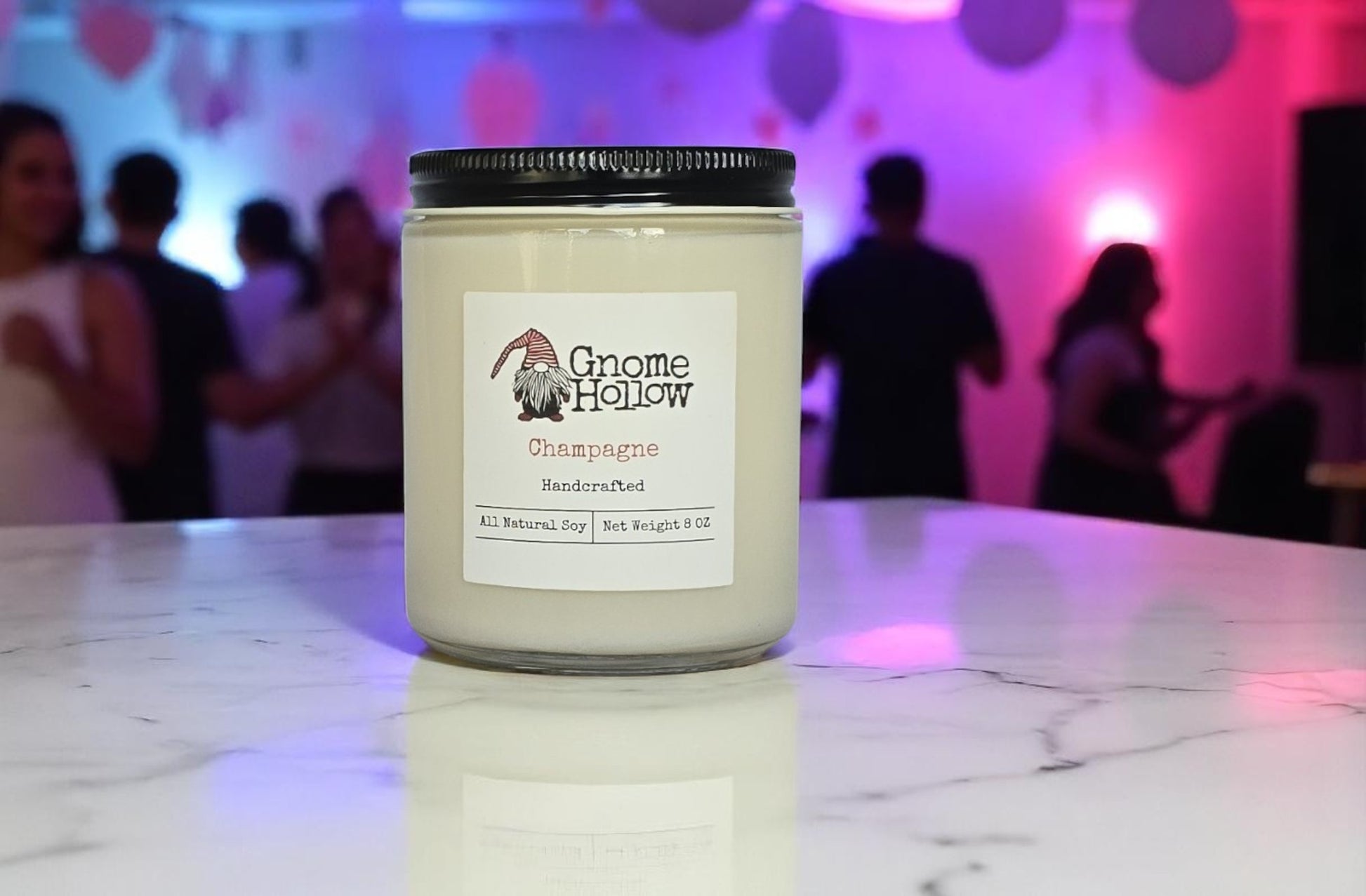 Champagne candle on a marble surface with a blurred background of people and pink lighting.