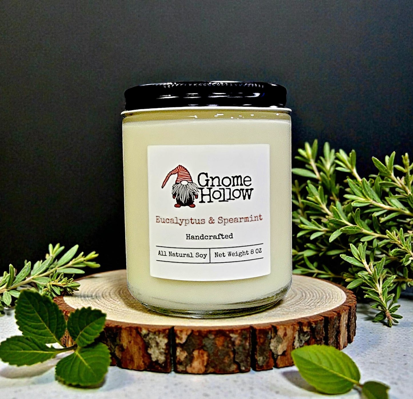 Gnome Hollow candle on a wooden coaster with greenery