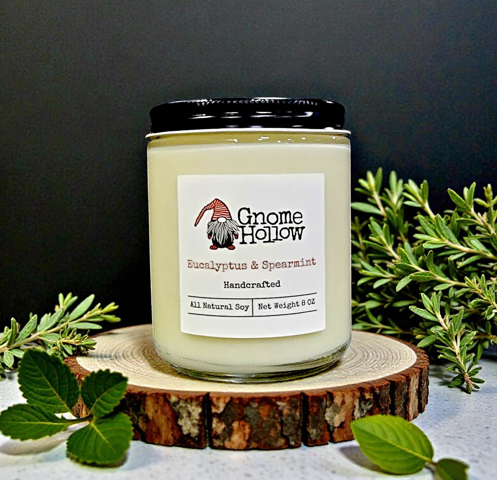 Gnome Hollow candle on a wooden coaster with greenery