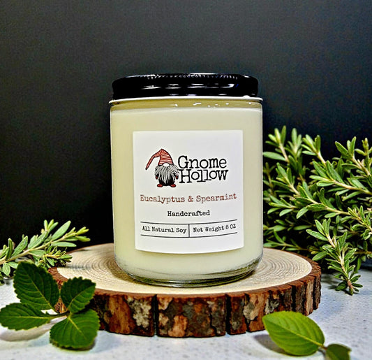Gnome Hollow candle on a wooden coaster with greenery