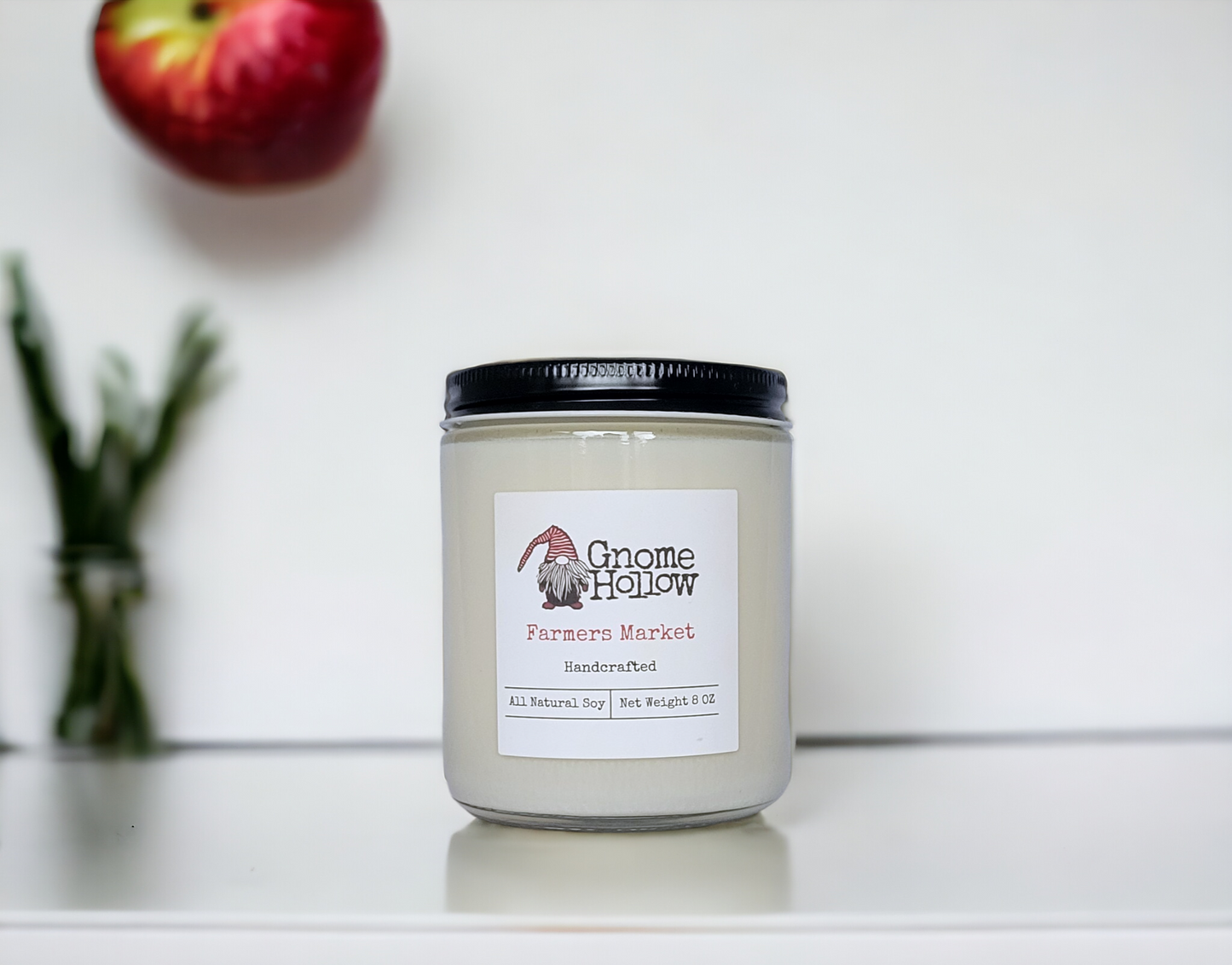 Farmers Market Candle on a white counter with a blurred apple in the background