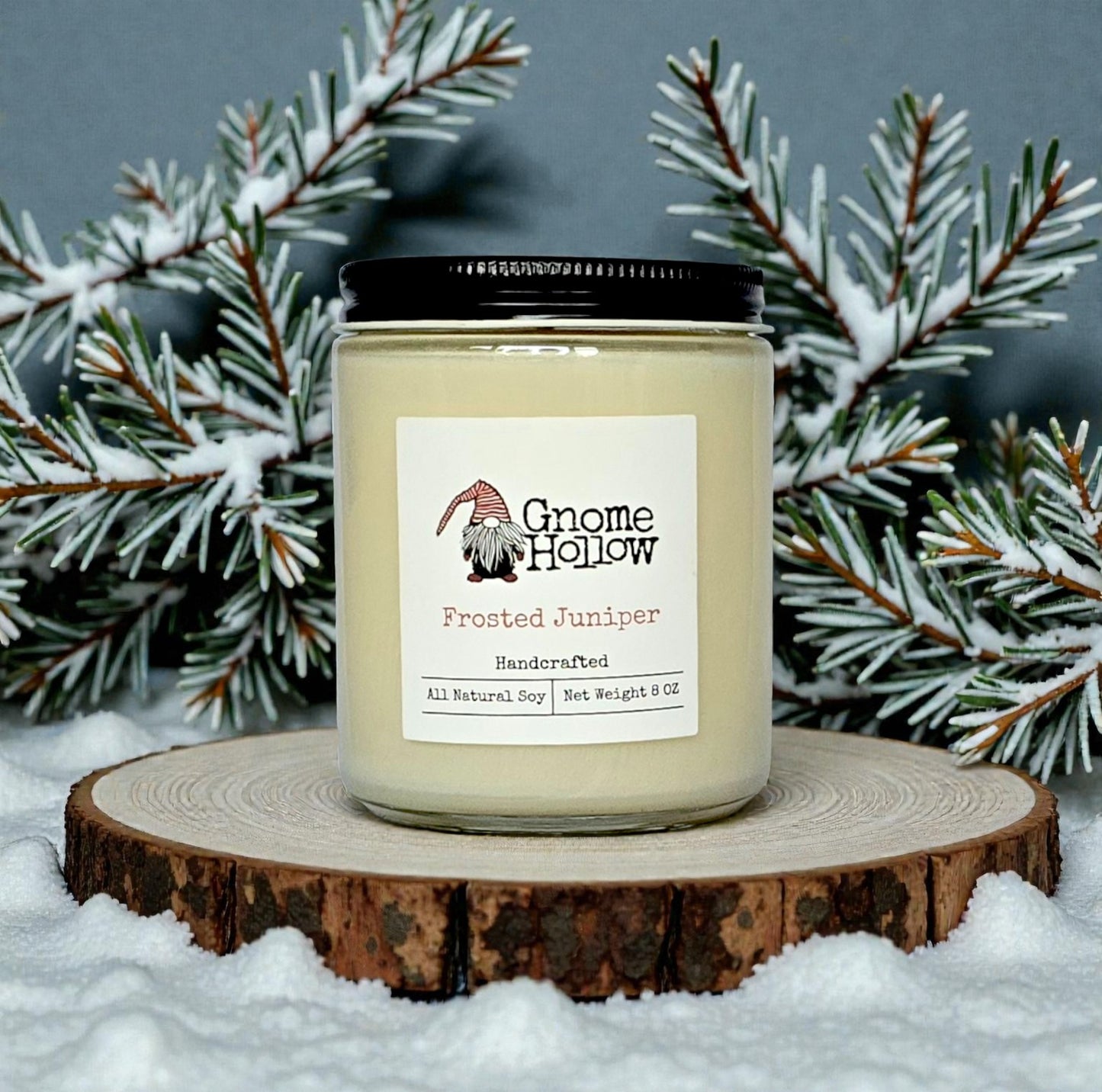 Candle in snow with juniper