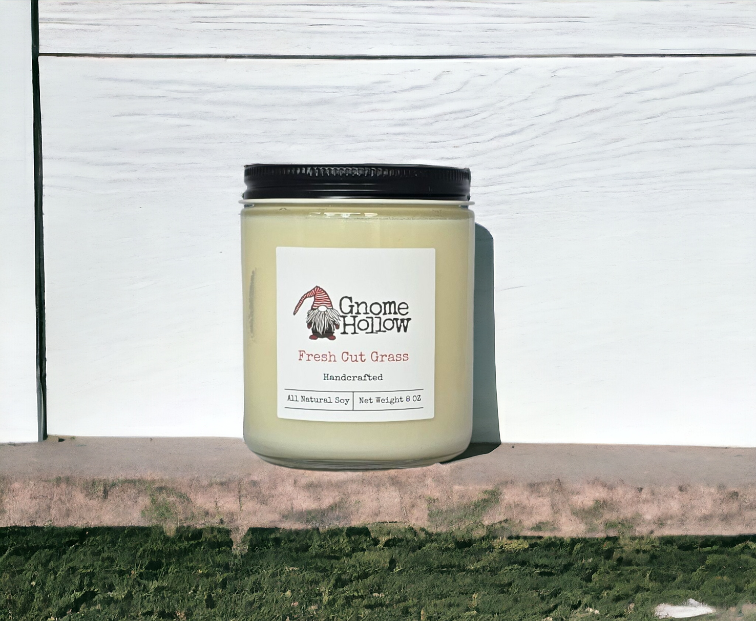 Fresh Cut Grass candle sitting on a ledge with a white plank wall behind