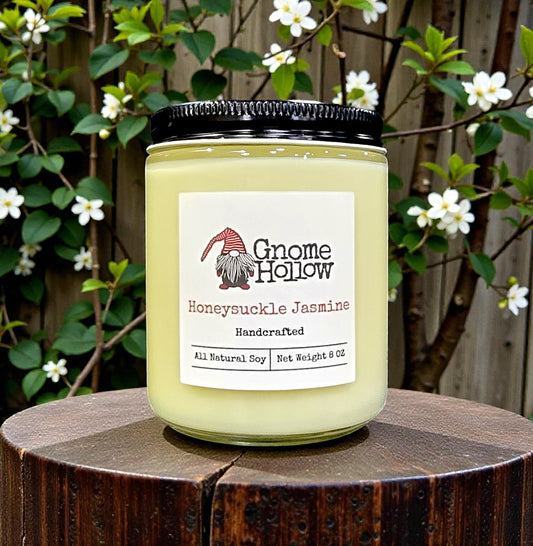 Gnome Hollow candle labeled 'Honeysuckle Jasmine' on a wooden surface with a natural background