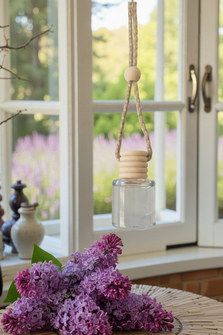 Decorative hanging bottle with wooden elements in front of a window with a view of greenery.