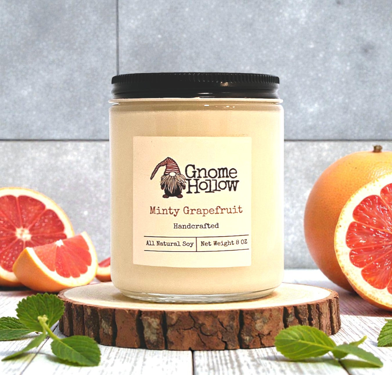 Gnome Hollow Minty Grapefruit candle on a wooden coaster with grapefruits in the background