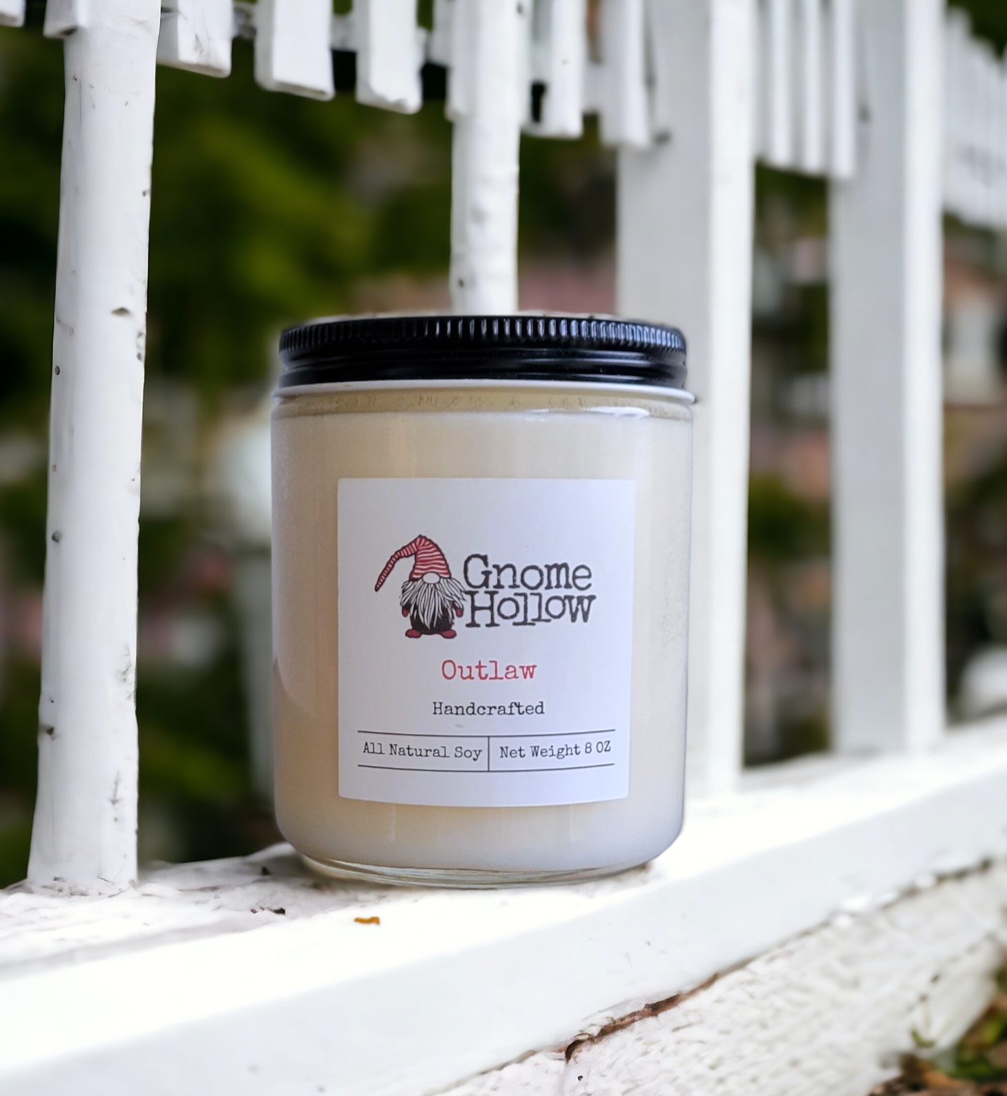 Outlaw candle sitting on a white picket fence