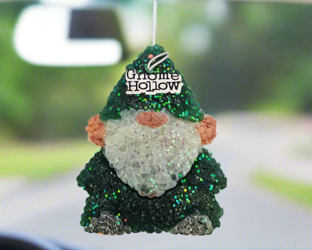 Green gnome air freshener handing from a rearview mirror