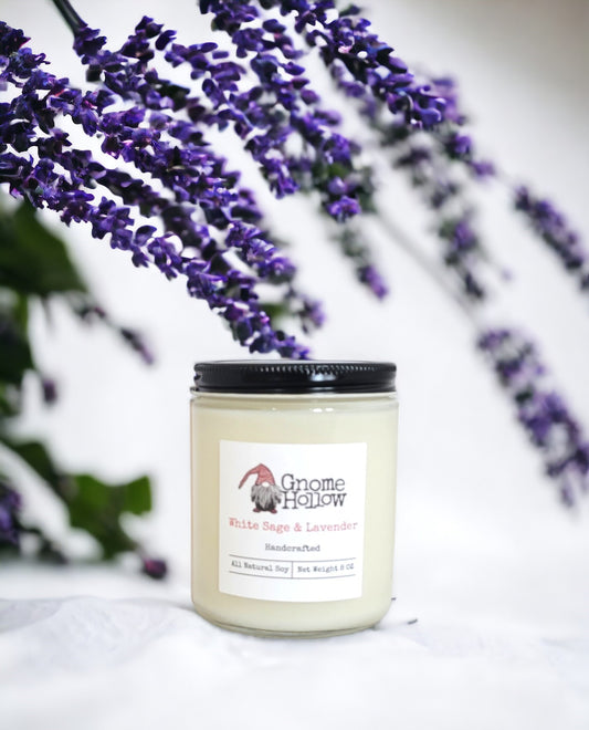 White Sage + Lavender candle on a white surface with lavender in the background
